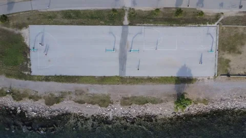 Aerial top down view of basketball court beside coastal park and trees Stock Footage 343945068