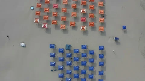 Aerial top down view of a beach filled with beach tents in red and blue Stock Footage 146755253