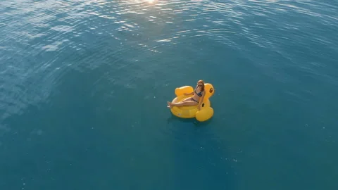 Aerial top down view of a beautiful woman relaxing on an inflatable yellow duck Stock-Footage 112646648