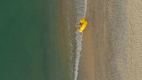 Aerial top down view of a beautiful woman walking with inflatable yellow duck Stock Footage 112648192
