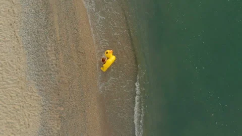 Aerial top down view of a beautiful woman walking with inflatable yellow duck Stock-Footage 112648667