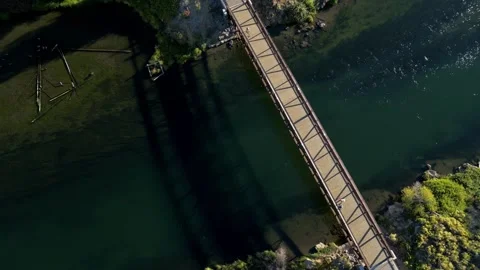 Aerial Top Down View of Beautiful Clear River with Footbridge and Person Stock Footage 249748211