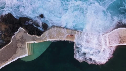 Aerial top down view of beautiful woman walking on the edge of a natural  pool Video stock 299960085