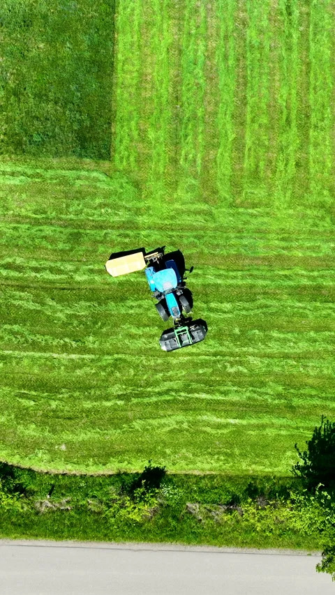Aerial Top Down View of Blue Tractor Mowing Green Grass Field Video stock 336567668