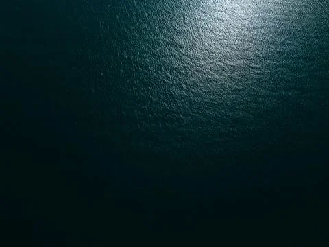 Aerial top down view of a blue sea water surface with sun reflection Stock Photos