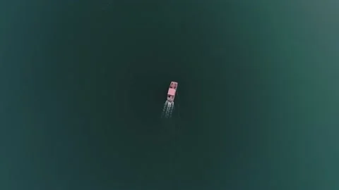 Aerial top down view of a boat with people slowly sailing on the surface of Lake Stock Footage 201251953