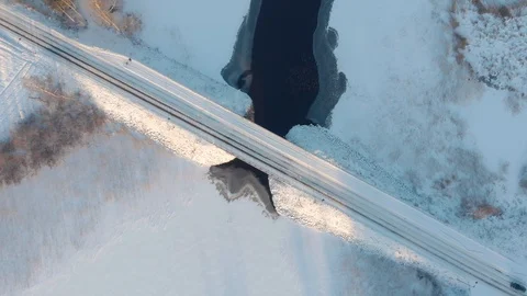 Aerial top down view of car driving across snowy road through winter bridge Stock Footage 123607465