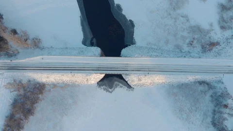 Aerial top down view of car driving across snowy road through winter bridge Stock Footage 123608352