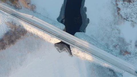 Aerial top down view of car driving across snowy road through winter bridge Stock Footage 123608683