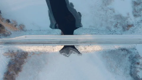 Aerial top down view of car driving across snowy road through winter bridge Stock Footage 123609192
