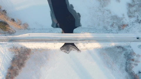 Aerial top down view of car driving across snowy road through winter bridge Stock Footage 123609462