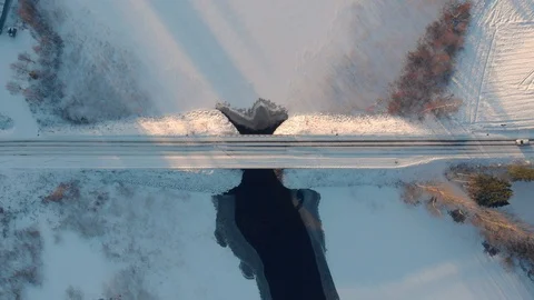 Aerial top down view of car driving across snowy road through winter bridge Stock Footage 123609771