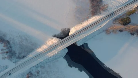 Aerial top down view of car driving across snowy road through winter bridge Stock Footage 123610015