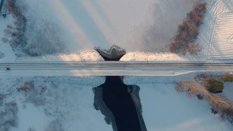 Aerial top down view of car driving across snowy road through winter bridge Stock Footage 123610016
