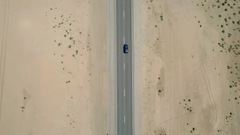 Aerial top down view of a car driving on a highway road between sands with Stock-Footage 165318335