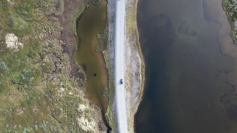 Aerial Top-Down View of Car Driving Along Road Between Lake and Wetlands Stock Footage 343507420