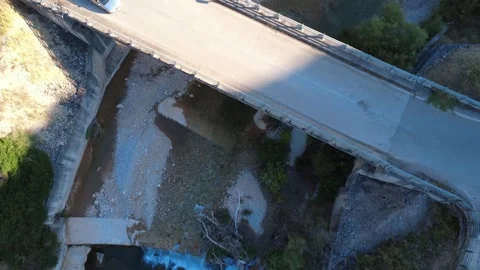 Aerial top down view of a car crossing a bridge over a wild waterfall Stock Footage 343962829