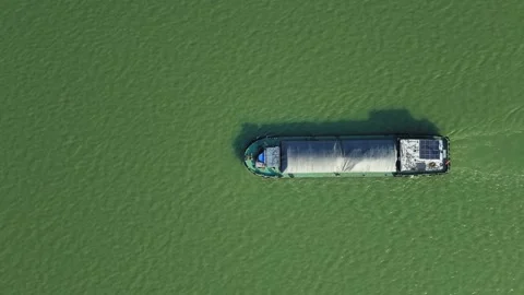 Aerial top down view of a cargo vessel navigates tranquil waters in green river Stock Footage 310117549