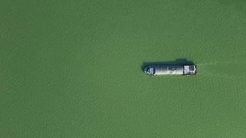 Aerial top down view of a cargo vessel navigates tranquil waters in green river Stock Footage 310118084