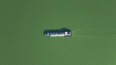 Aerial top down view of a cargo vessel navigates tranquil waters in green river Stock Footage 311557829
