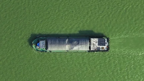 Aerial top down view of a cargo vessel navigates tranquil waters in green river Vídeo Stock 313582667