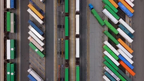 Aerial top-down view of cargo trucks and trains at intermodal terminal in Stock Footage 318991310