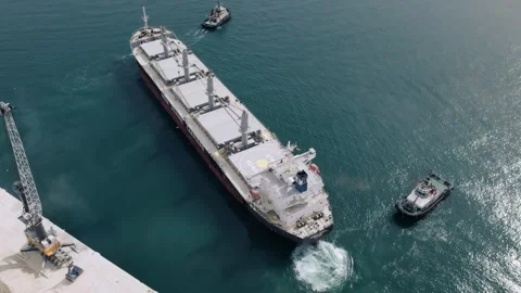 Aerial Top Down View of Cargo Ship Assisted by Tugboats Stock Footage 344529014