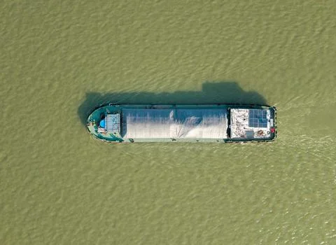Aerial top down view of a cargo vessel navigates tranquil waters in green river 스톡 사진