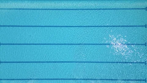 Aerial top-down view of a clear blue swimming pool with lane markings and Stock Footage 310796922
