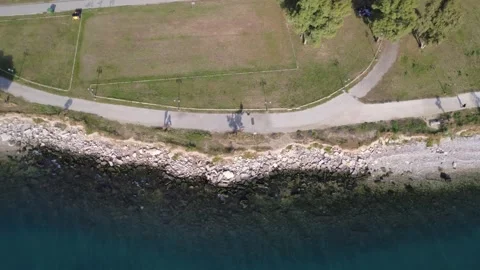 Aerial top down view of coastal promenade beside rocky sea shoreline Stock Footage 343944881