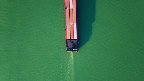 Aerial top down view of container ship navigates calm ocean waters near coastal Vídeo Stock 310117943