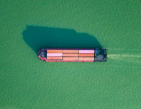 Aerial top down view of container ship navigates calm ocean waters near coastal 스톡 사진