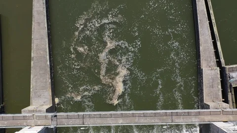 Aerial top down view of dirty water whirlpool under dam of hydroelectric plant Stock Footage 107375383
