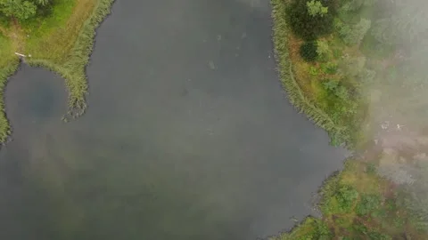 Aerial top down view drone flies through rain clouds rolling over forest by lake Stock Footage 153054503
