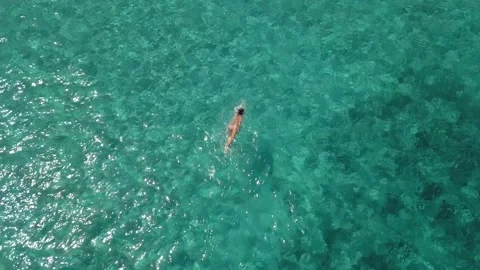 Aerial top down view - drone follows swimmer in sea 4K Stock Footage 153328073
