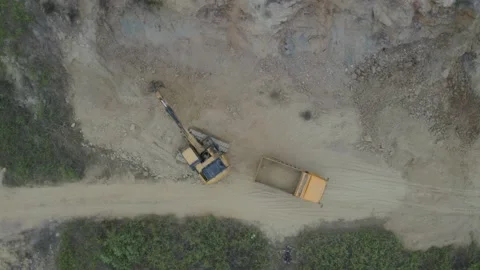 Aerial top down view of an excavator that is filling a truck with sand Stock Footage 146754420