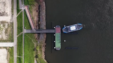 Aerial top down view of ferry departing from riverbank dock Видео 336618831