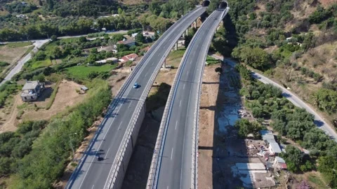 Aerial top-down view following curved highway overpass into tunnel Stock Footage 343961512