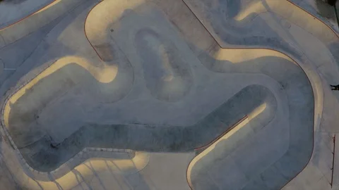 Aerial top-down view of guys riding skates across a large skatepark Stock Footage 128404998