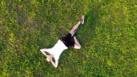 Aerial top down view of happy young man laying on summer grass. Man relaxing Stock Footage 128571915