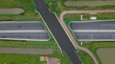 Aerial top down view of highway traffic driving under a canal and bike path Stock Footage 338015525