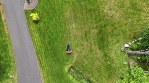 Aerial Top-Down View of Landscaper Mowing Lush Green Lawn in Suburban Yard Видео 335029464