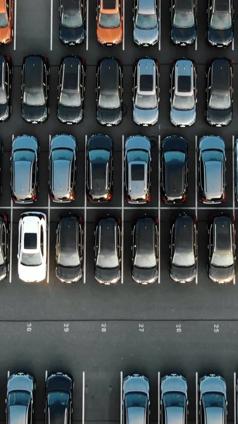 Aerial top down view of a large car park with new vehicles perfectly aligned in Stock Footage 344985437