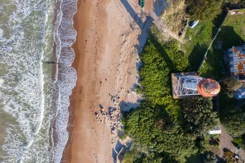 Aerial top down view of lighthouse with red top and white base. Blue sea Stock Photos