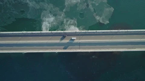 Aerial top down view of low-water bridge across the bay with moving car. Active Stock Footage 144936046