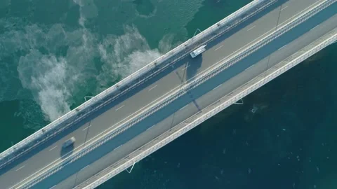 Aerial top down view of low-water bridge across the bay with moving car. Active Stock Footage 144936161