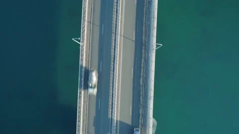 Aerial top down view of low-water bridge across the bay with moving car. Active Stock Footage 144936186