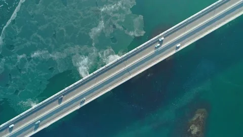 Aerial top down view of low-water bridge across the bay with moving car. Active Stock Footage 144937107