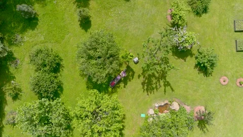 Aerial top-down view of a man mowing grass with a lawn mower in a backyard. Stockbeeldmateriaal 277426664