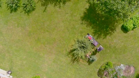 Aerial top-down view of a man mowing grass with petrol lawn mower in a backyard. Stock Footage 278253059